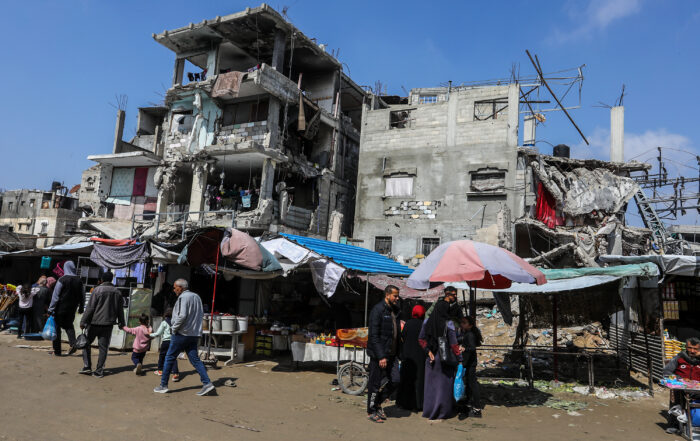 On the market sidewalk… A mother repairs banknotes to resist the siege in Gaza